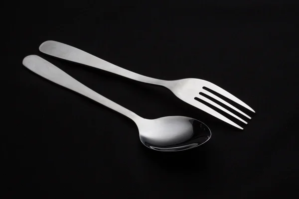 Tenedor plateado con cuchara aislada sobre fondo negro — Foto de Stock