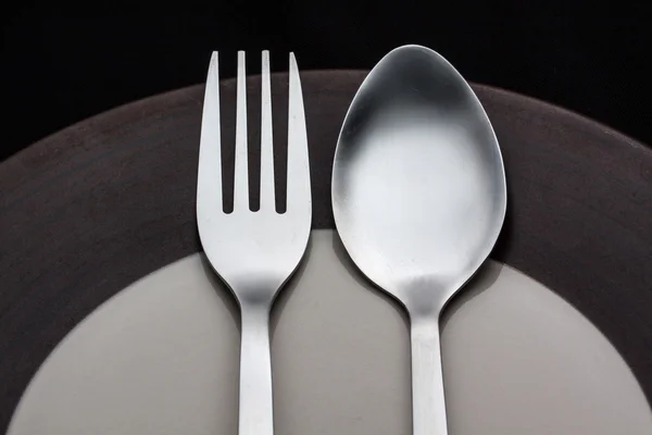Platen met een zilveren vork en lepel geïsoleerd op zwarte pagina — Stockfoto
