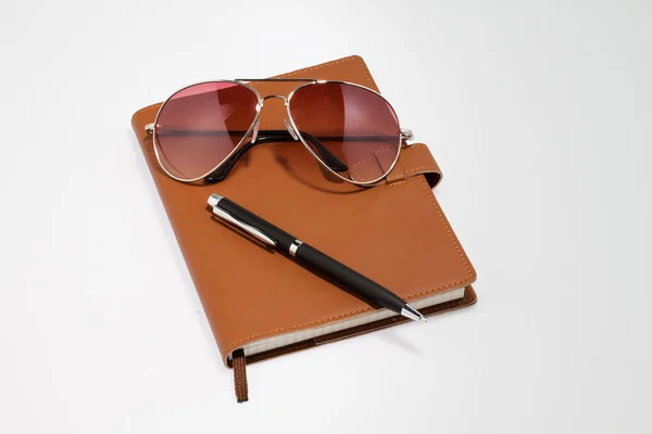 Notebook com óculos de sol e caneta — Fotografia de Stock