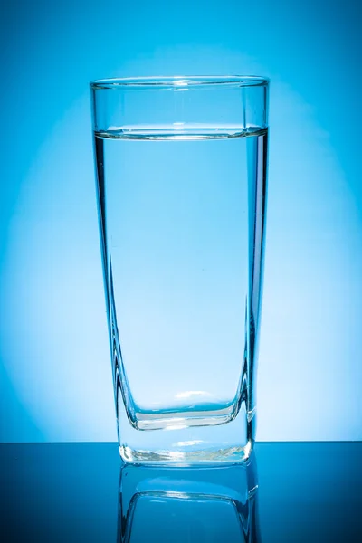 Glass of water isolated on blue background.
