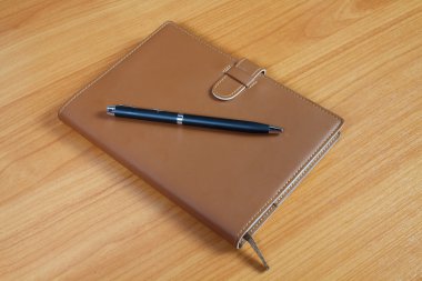 kahverengi defter ve kalem ahşap arka plan üzerinde