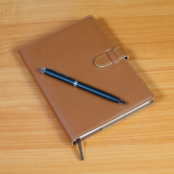 Barna notebook és a toll, mint fából készült háttér — Stock Fotó
