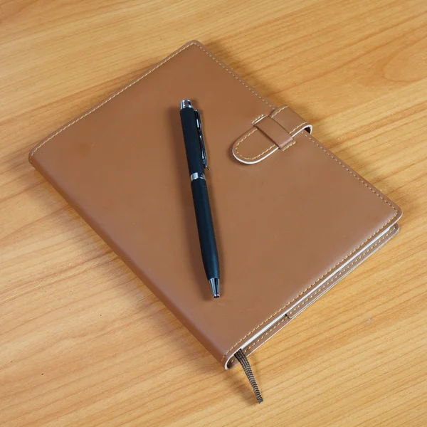 Brown notebook and pen over wooden background — Stock Photo, Image