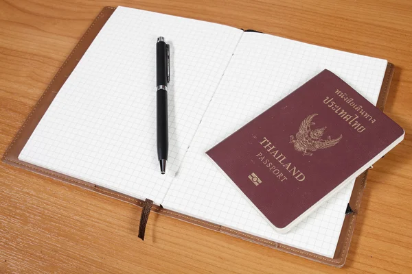 Notebook aberto com passaporte e caneta sobre fundo de madeira — Fotografia de Stock