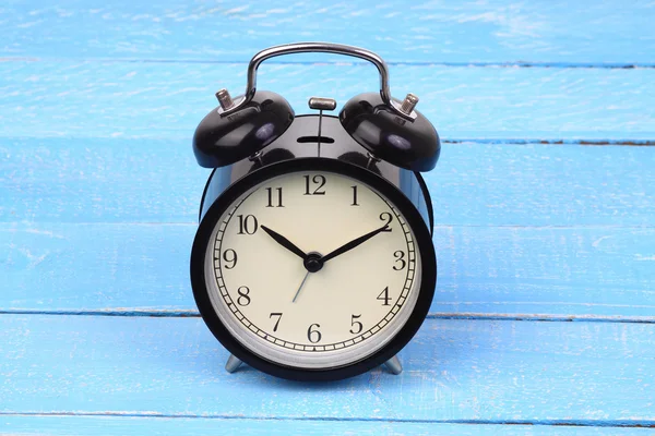 Classic alarm clock on blue wood background. — Stock Photo, Image