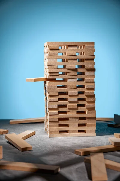 青の背景に木製のブロックの塔とランダムに木製のブロックを横にJengaゲーム ゲームを通じたビジネスエンジニアリング 戦略と集中のための活動 テキストのためのフリースペース — ストック写真