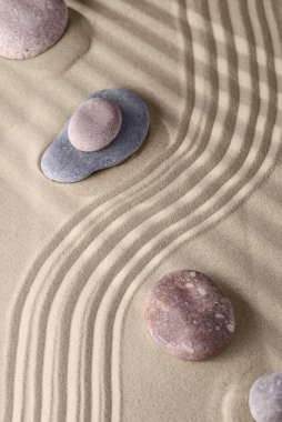 Kumda pürüzsüz çizgiler ve kaya bahçesindeki yuvarlak taşlar, rahatlama ve ruhsal uyum için. Meditasyon, rahatlama, denge ve maneviyat uyumu ve gevşeme Zen bahçesi