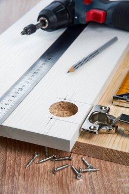 Çizgili tahtaya mobilya menteşeleri, aletler ve aksesuarlar yerleştirilmeli. Evde küçük marangozluk işleri, ev sahibi konsepti, evin kendi kendini tamir etmesi.