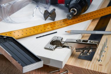 Çizgili tahtaya mobilya menteşeleri, aletler ve aksesuarlar yerleştirilmeli. Evde küçük marangozluk işleri, ev sahibi konsepti, evin kendi kendini tamir etmesi.