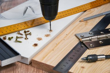 Çizgili tahtaya mobilya menteşeleri, aletler ve aksesuarlar yerleştirilmeli. Evde küçük marangozluk işleri, ev sahibi konsepti, evin kendi kendini tamir etmesi.