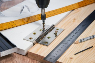 Çizgili tahtaya mobilya menteşeleri, aletler ve aksesuarlar yerleştirilmeli. Evde küçük marangozluk işleri, ev sahibi konsepti, evin kendi kendini tamir etmesi.