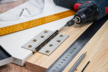 Çizgili tahtaya mobilya menteşeleri, aletler ve aksesuarlar yerleştirilmeli. Evde küçük marangozluk işleri, ev sahibi konsepti, evin kendi kendini tamir etmesi.