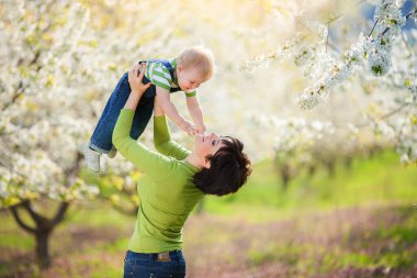 Mutlu kadın ve çocuk çiçek açan bahar bahçesinde.