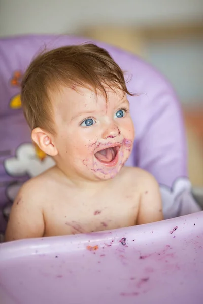 Adorable bébé mangeant sur une chaise de bébé et faisant un gâchis. Photos De Stock Libres De Droits