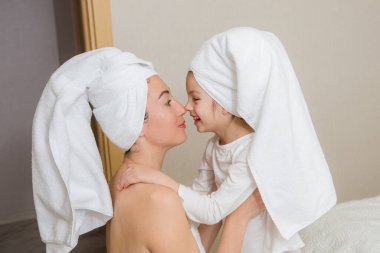 Anne ve kızı yatakta oynuyorlar ve sarılıyorlar. Sevgi dolu bir aile. Anneler günün kutlu olsun..