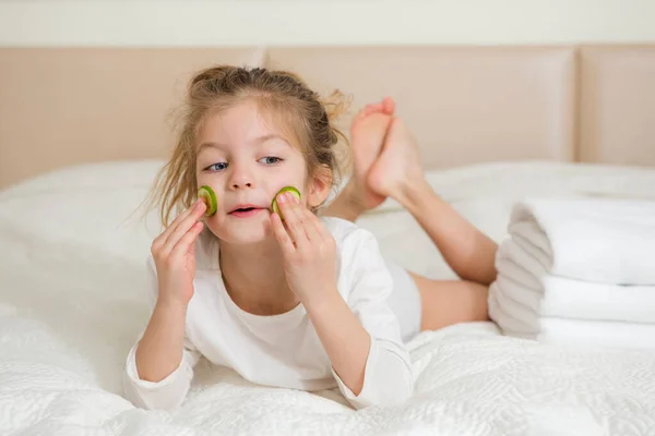 Gülümseyen mutlu bir kız çocuğunun portresi. 5 yaşındaki tatlı kız yatakta dinleniyor. Cilt bakımı kavramı.