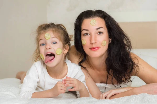 Anne ve kızı yatakta oynuyorlar ve sarılıyorlar. Sevgi dolu bir aile. Anneler günün kutlu olsun..