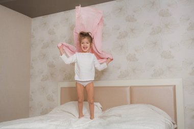 Mutlu, gülümseyen, komik yüzlü, yatakta dinlenen kız çocuğu. Sevimli bir kızın portresi..