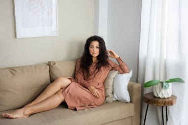 Güzel, kıvırcık saçlı, evde dinlenen genç bir kadın..