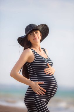 Kumsalda siyah elbiseli güzel hamile kadın..