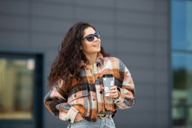 Kıvırcık saçlı, gülümseyen, şık bir kadın.