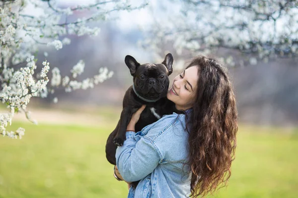 Beautiful young woman playing with bulldog outdoors. Cute hipster girl hugs and kissed her dog. — Stock Photo, Image