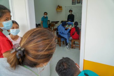 BALI / INDONESIA-MAY 28 2021: Bir ENT doktoru bir pediyatrik hastanın kulaklarını, burnunu ve boğazını muayene ediyor. COVID-19 salgını sırasında, ENT incelemeleri çok risklidir çünkü virüsün bulunduğu organlardaki hastalarla doğrudan temasta bulunurlar. 