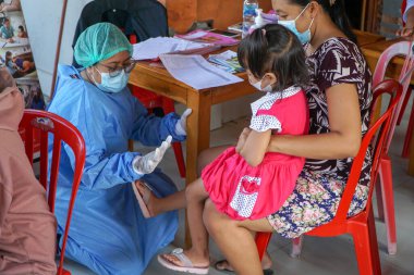 DENPASAR, BALI / JUNE 14 Haziran 2021: bir fizyoterapist çocuğun büyüme ve gelişimi hakkında açıklama yapıyor. COVID19 salgını sırasında fizyoterapistler virüsün bulaşmasını önlemek için PPE kullandılar.
