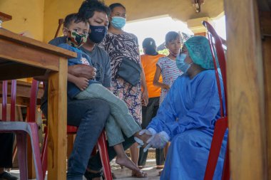 DENPASAR, BALI / JUNE 14 Haziran 2021: bir fizyoterapist çocuğun büyüme ve gelişimi hakkında açıklama yapıyor. COVID19 salgını sırasında fizyoterapistler virüsün bulaşmasını önlemek için PPE kullandılar.