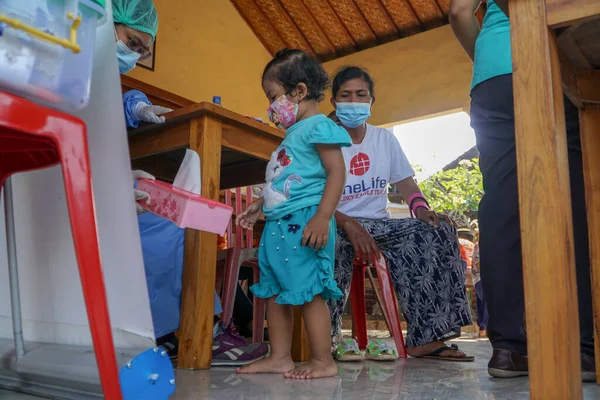DENPASAR, BALI / JUNE 14 Haziran 2021: bir fizyoterapist çocuğun büyüme ve gelişimi hakkında açıklama yapıyor. COVID19 salgını sırasında fizyoterapistler virüsün bulaşmasını önlemek için PPE kullandılar.