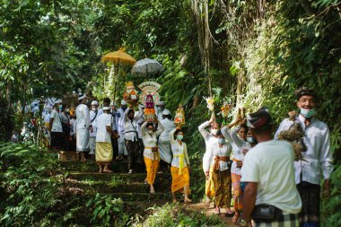 Gianyar, Bali-Mayıs 11 2021 Balili Hindu topluluğu Ubud 'daki orman ve nehir için temizleme töreni düzenliyor. COVID-19 'dan kaçınmak için adak getirip tıbbi maske takıyorlar.