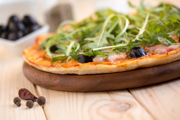 Homemade pizza with bacon, olives and arugula — Stock Photo, Image