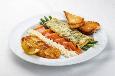 Kahvaltıda. Somon ve kuşkonmazlı omlet, fırında patates ve kızarmış ekmek.