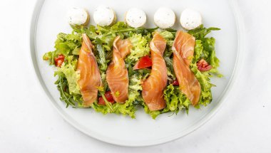 Beyaz tabakta peynirli somon salatası.