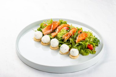 Beyaz tabakta peynirli somon salatası.