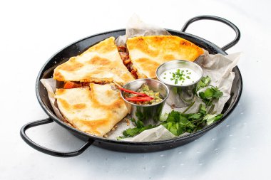 Guacamole ve krema soslu bir tavada Quesadilla. Geleneksel Meksika yemeği. Hafif arkaplanda