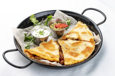 Guacamole ve krema soslu bir tavada Quesadilla. Geleneksel Meksika yemeği. Hafif arkaplanda