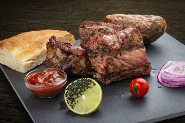 Fırında patates, kibrit ve kırmızı soslu ızgara dana biftek. Taş bir tabakta servis edilir.