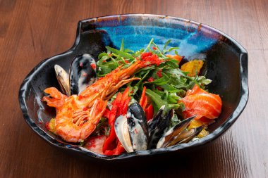 Deniz ürünleri salatası: karides, midye, somon, roka ve portakal. Dekoratif bir tabakta