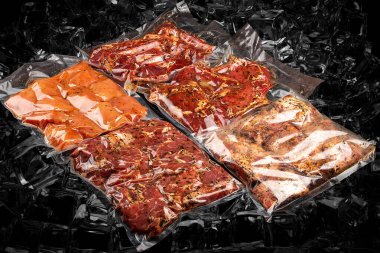 Süpürgeyle paketlenmiş, buzlu arka planda farklı etler. Yarı pişmiş.