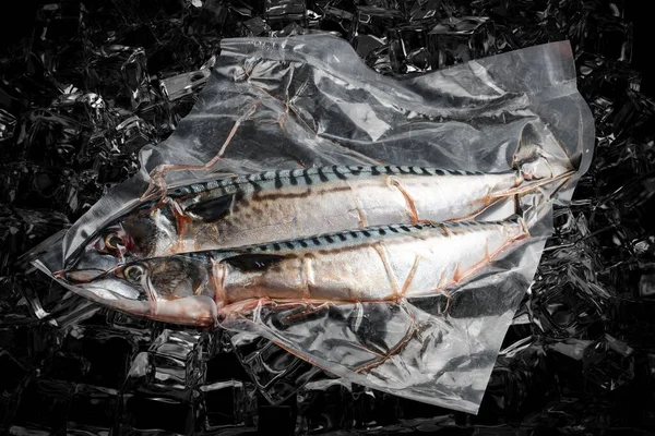 Vacuum-packed fish, on dark ice background, mackerel. Semifinished.