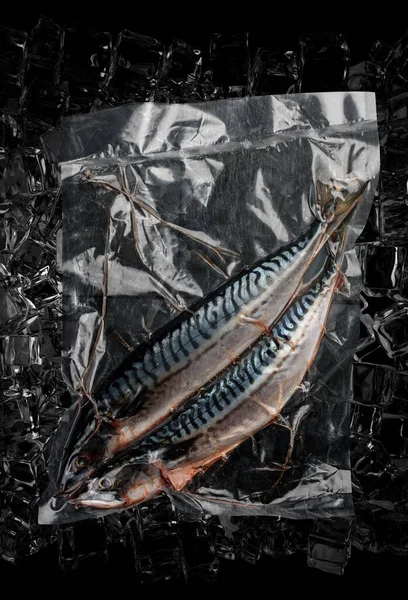 Vacuum-packed fish, on dark ice background, mackerel. Semifinished.Top view.