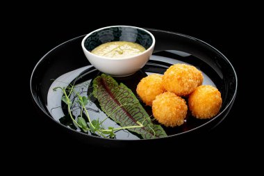 Ballı hardal soslu peynir topları. Parlak siyah bir tabakta. Siyah bir arkaplanda