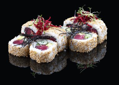 Parlak siyah arka planda susamlı suşi rulosu.