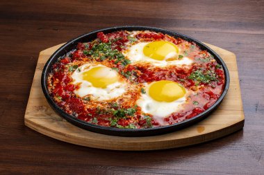 Evde çırpılmış yumurta ve tavada domatesler. Ahşap bir arka planda. Kahvaltı.