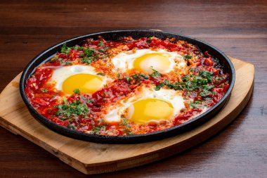 Evde çırpılmış yumurta ve tavada domatesler. Ahşap bir arka planda. Kahvaltı.