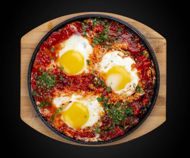 Evde çırpılmış yumurta ve tavada domatesler. Siyah bir arka planda. Kahvaltı.