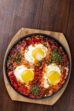 Evde çırpılmış yumurta ve tavada domatesler. Ahşap bir arka planda. Kahvaltı.