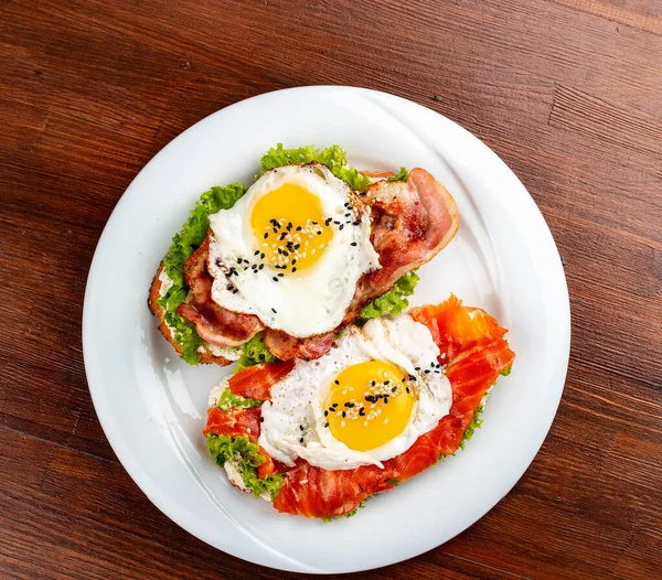 Toast with salmon, bacon and cream cheese.  On a wooden background. Breakfast