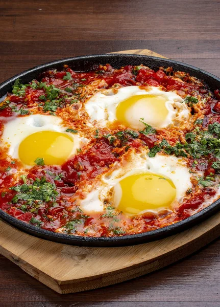 Evde çırpılmış yumurta ve tavada domatesler. Ahşap bir arka planda. Kahvaltı.